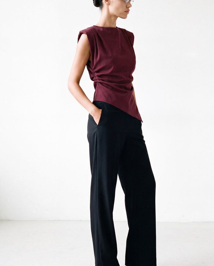 Padded-Shoulder Pleated Top in burgundy worn by model with black trousers